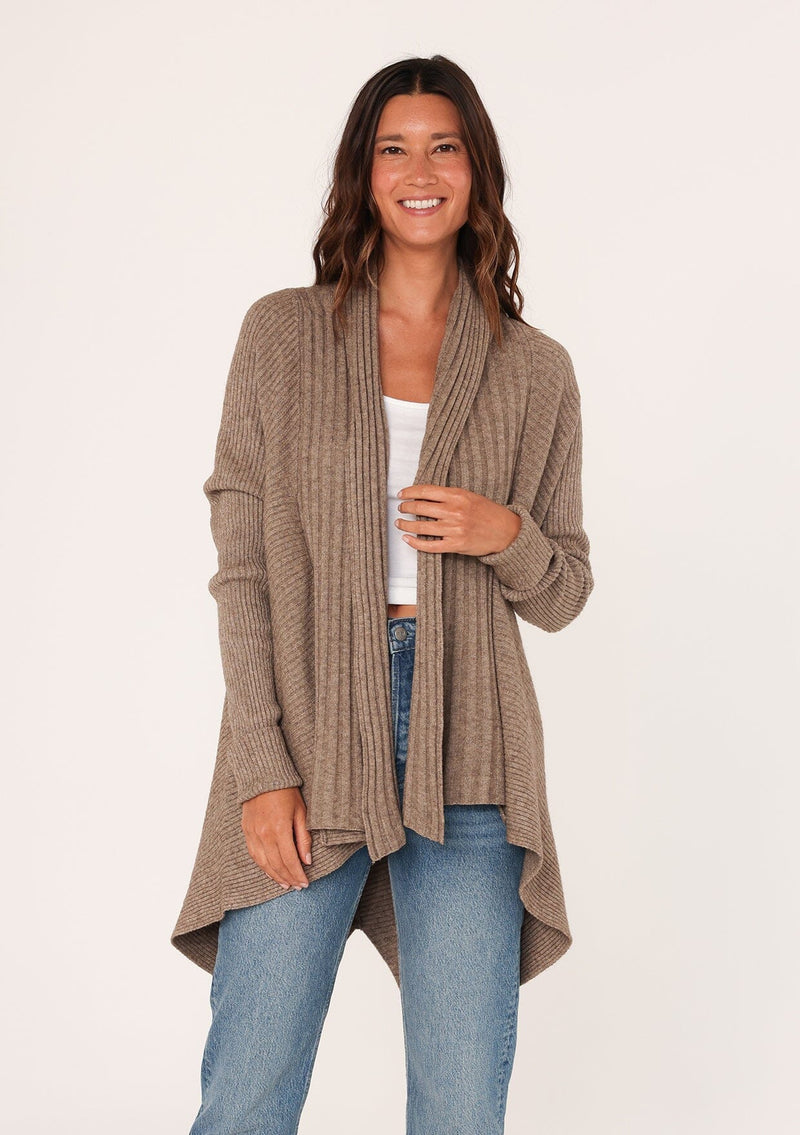 [Color: Mushroom] A front facing image of a brunette model wearing a brown shawl cardigan with a ribbed texture, open front, and a back vent detail. Cozy and relaxed for the fall season. 
