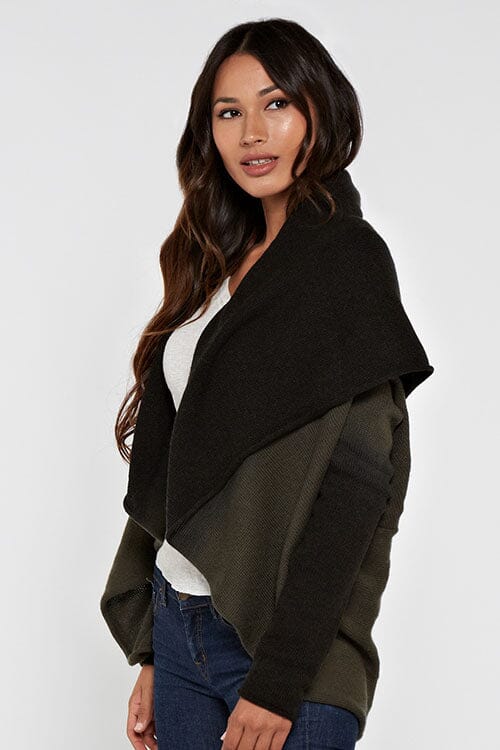 [Color: Olive/Black] A side facing image of a blonde model wearing a dip dyed cocoon cardigan with a shawl collar and long sleeves. A versatile cardigan that can transition from a duster to a mid-length cardigan. 