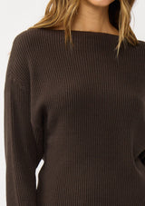 [Color: Dark Brown] A detail image of a blonde model wearing a brown waffle knit pullover sweater. With long sleeves, a relaxed fit, and a wide neckline that can be worn off the shoulder.
