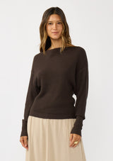 [Color: Dark Brown] A front facing image of a blonde model wearing a brown waffle knit pullover sweater. With long sleeves, a relaxed fit, and a wide neckline that can be worn off the shoulder.