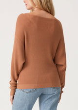 [Color: Clay] A back facing image of a blonde model wearing a clay brown waffle knit pullover sweater. With long sleeves, a relaxed fit, and a wide neckline that can be worn off the shoulder.