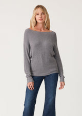 [Color: Heather Charcoal] A full body front facing image of a blonde model wearing a dark heather grey waffle knit pullover sweater. With long sleeves, a relaxed fit, and a wide neckline that can be worn off the shoulder.