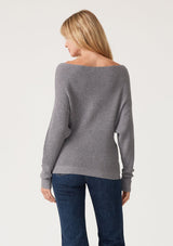 [Color: Heather Charcoal] A back facing image of a blonde model wearing a dark heather grey waffle knit pullover sweater. With long sleeves, a relaxed fit, and a wide neckline that can be worn off the shoulder.