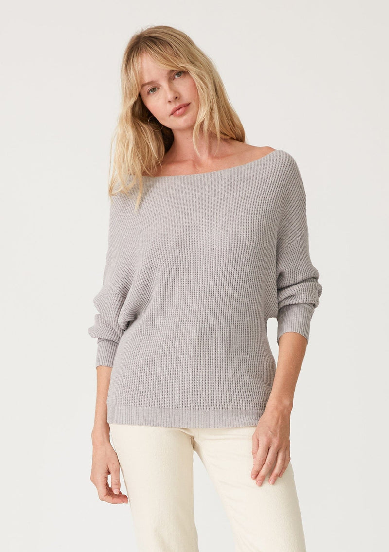 [Color: Light Heather Grey] A front facing image of a blonde model wearing a light heather grey waffle knit pullover sweater. With long sleeves, a relaxed fit, and a wide neckline that can be worn off the shoulder.