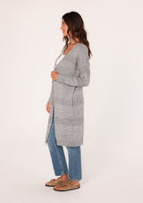 [Color: Heather Grey] A side view of a brunette woman modeling a long, open-front gray mélange knit cardigan over a white top and blue jeans.