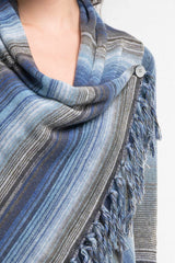 [Color: Heather Ocean/Grey] An image of a model wearing a striped shawl cardigan with a fringe trim and wrap button closure. 
