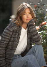 [Color: Heather Charcoal/Brown] A blonde model wearing a grey and brown melange stripe cardigan. Featuring a cozy shawl collar and front patch pockets. Perfect for casual fall outings. 