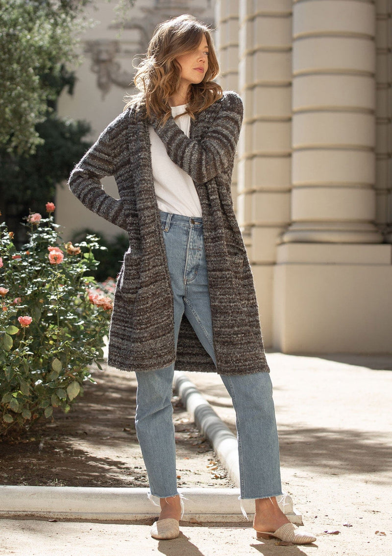 [Color: Heather Charcoal/Brown] A blonde model wearing a grey and brown melange stripe cardigan. Featuring a cozy shawl collar and front patch pockets. Perfect for casual fall outings. 