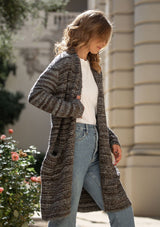 [Color: Heather Charcoal/Brown] A blonde model wearing a grey and brown melange stripe cardigan. Featuring a cozy shawl collar and front patch pockets. Perfect for casual fall outings. 