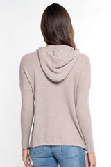 [Color: Heather Cement] A back facing image of a brunette model wearing a taupe waffle knit pullover with a drawstring hoodie, kangaroo pockets, and side slits with tie detail. 