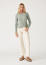 [Color: Dusty Sage] A full body front facing image of a blonde model wearing a dusty sage green waffle knit pullover sweater. With long sleeves, a wide crew neckline, and a twist front detail at the waist. 