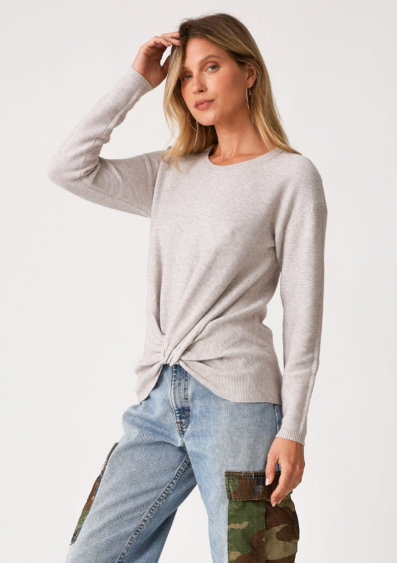 [Color: Heather Grey] A front facing image of a blonde model wearing a heather grey pullover sweater in a ribbed textured knit. With long sleeves, a crew neckline, long sleeves, a relaxed fit, and a knot front waist detail.