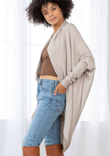 [Color: Heather Stone] A brunette model wearing a slouchy cardigan with a cocoon fit, shawl collar drape, and long dolman sleeves. This relaxed style is the perfect casual staple for any fall wardrobe. 