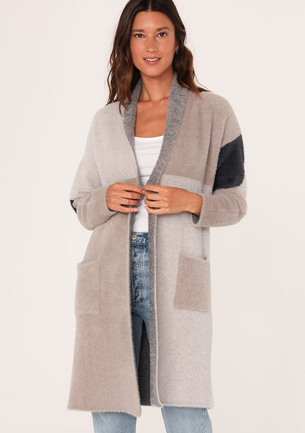 [Color: Grey/Charcoal] A front facing image of a brunette model wearing a soft and fuzzy mid length cardigan in a grey and taupe color block pattern. With an open front, long sleeves, and side pockets. 