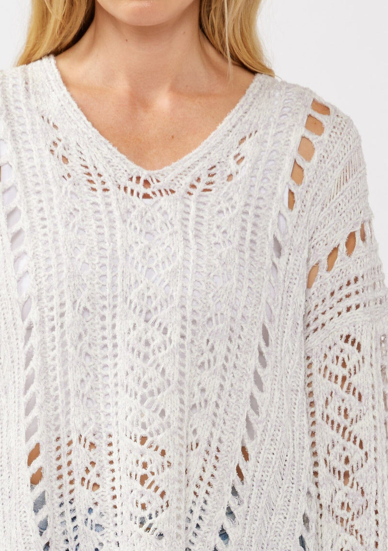 [Color: Lilac] A detail image of a blonde model wearing a light purple open knit crochet pullover sweater with a v-neckline long sleeves, dropped shoulders, and a side vents. Designed for a relaxed look and fit for the spring season. 