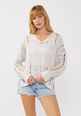 [Color: Lilac] A front facing image of a blonde model wearing a light purple open knit crochet pullover sweater with a v-neckline long sleeves, dropped shoulders, and a side vents. Designed for a relaxed look and fit for the spring season. 