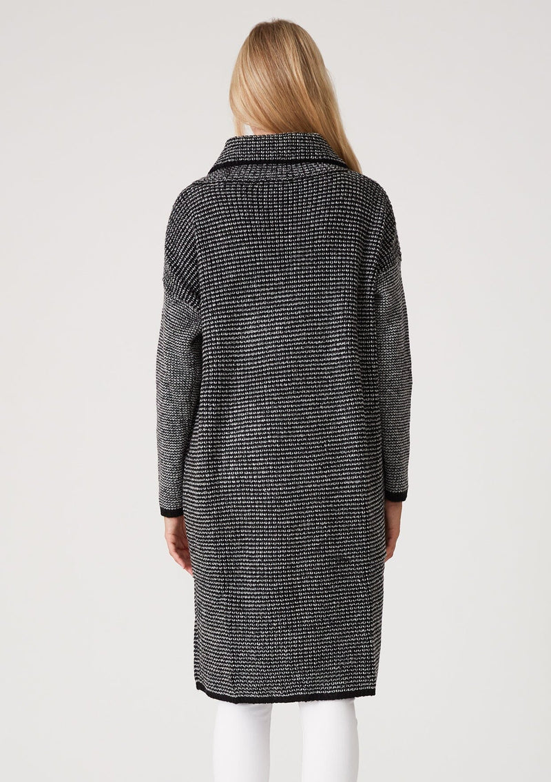 [Color: Black Multi] A back facing image of a blonde model wearing a black and white multi knit duster cardigan. A mid length cardigan sweater with an oversize collared neckline, a snap button front, side pockets, and contrast trim. 