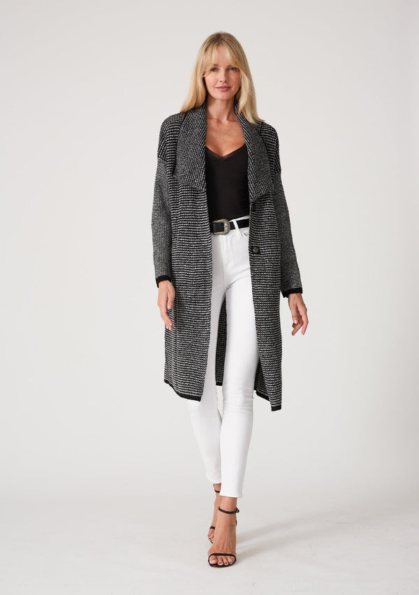 [Color: Black Multi] A front facing image of a blonde model wearing a black and white multi knit duster cardigan. A mid length cardigan sweater with an oversize collared neckline, a snap button front, side pockets, and contrast trim. 