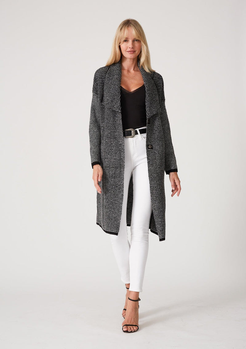 [Color: Black Multi] A front facing image of a blonde model wearing a black and white multi knit duster cardigan. A mid length cardigan sweater with an oversize collared neckline, a snap button front, side pockets, and contrast trim. 