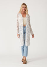 [Color: Ivory/Coral] A full body front facing image of a blonde model wearing an ivory speckled knit crochet cardigan. A lightweight sweater with long sleeves, a mid length, and an open front. 