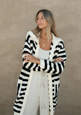 [Color: Black/White] A front facing image of a blonde model wearing a mid length cardigan in a black and white stripe. With long sleeves, a collared neckline, an open front, and side pockets.
