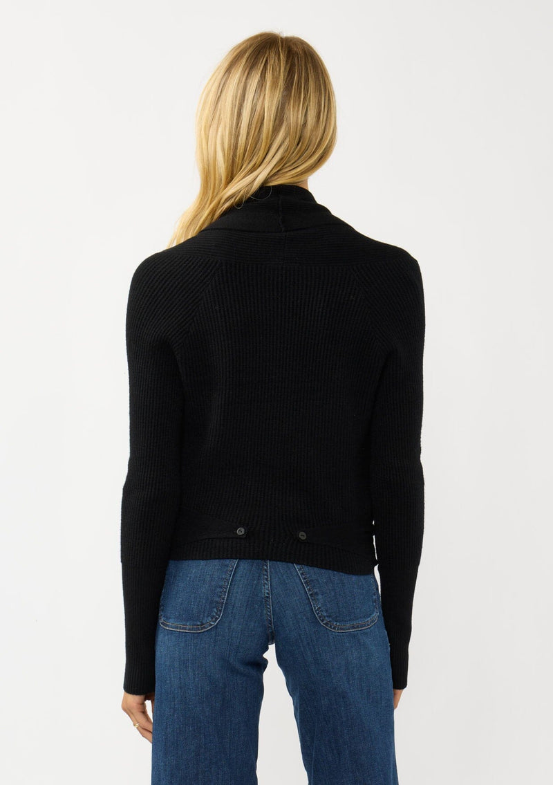 [Color: Black] A photo of a Lovestitch model wearing a chic black waffle knit wrap front sweater with long sleeves, a v neckline, and a button closure at the back. The long ties can be styled in multiple ways.