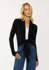 [Color: Black] A photo of a Lovestitch model wearing a chic black waffle knit wrap front sweater with long sleeves, a v neckline, and a button closure at the back. The long ties can be styled in multiple ways.