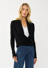 [Color: Black] A photo of a Lovestitch model wearing a chic black waffle knit wrap front sweater with long sleeves, a v neckline, and a button closure at the back. The long ties can be styled in multiple ways.