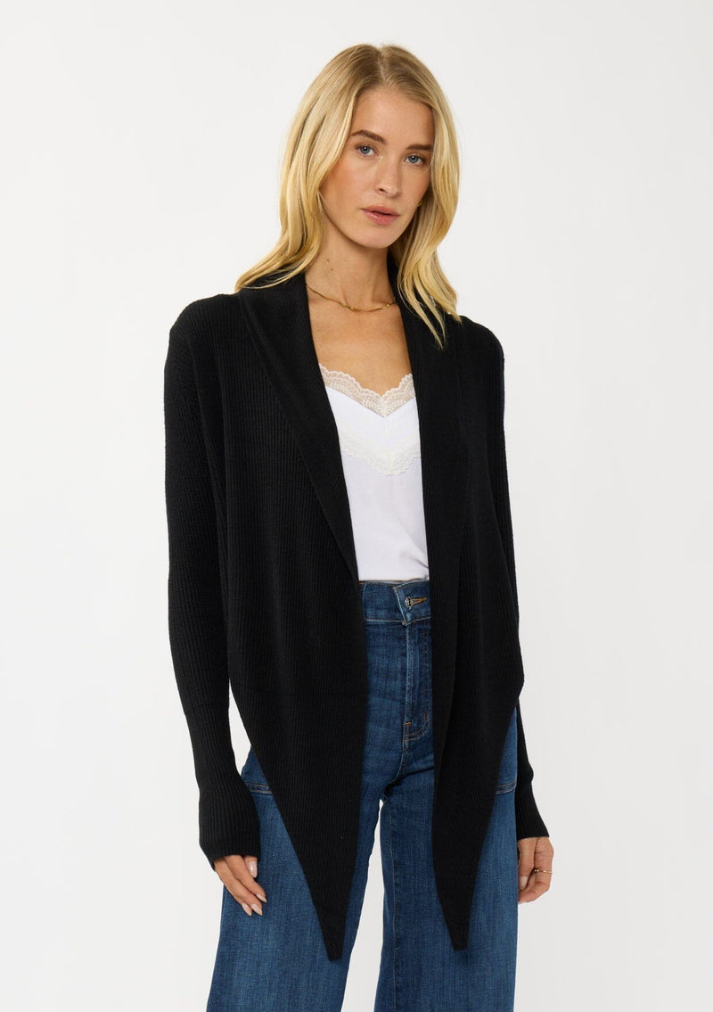 [Color: Black] A photo of a Lovestitch model wearing a chic black waffle knit wrap front sweater with long sleeves, a v neckline, and a button closure at the back. The long ties can be styled in multiple ways.