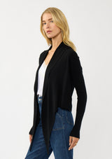 [Color: Black] A photo of a Lovestitch model wearing a chic black waffle knit wrap front sweater with long sleeves, a v neckline, and a button closure at the back. The long ties can be styled in multiple ways.