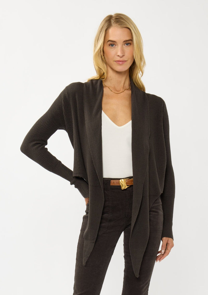 [Color: Dark Brown] A photo of a Lovestitch model wearing a chic brown waffle knit wrap front sweater with long sleeves, a v neckline, and a button closure at the back. The long ties can be styled in multiple ways.