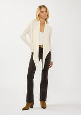 [Color: Natural] A photo of a Lovestitch model wearing a chic ivory waffle knit wrap front sweater with long sleeves, a v neckline, and a button closure at the back. The long ties can be styled in multiple ways.