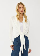 [Color: Winter White] A photo of a Lovestitch model wearing a chic white waffle knit wrap front sweater with long sleeves, a v neckline, and a button closure at the back. The long ties can be styled in multiple ways.