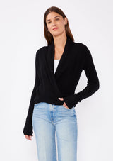 [Color: Black] A photo of a Lovestitch model wearing a chic black waffle knit wrap front sweater with long sleeves, a v neckline, and a button closure at the back. The long ties can be styled in multiple ways.