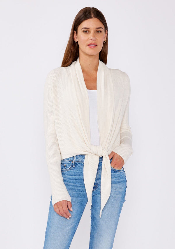 [Color: Natural] A photo of a Lovestitch model wearing a chic ivory waffle knit wrap front sweater with long sleeves, a v neckline, and a button closure at the back. The long ties can be styled in multiple ways.