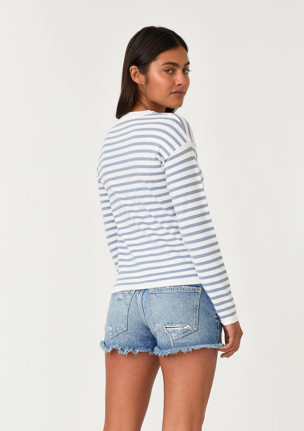 [Color: Ivory/Dusty Blue] A back facing image of a brunette model wearing a classic ivory and light blue striped knit pullover sweater. With long sleeves, a drop shoulder, a crew neckline, and a twist front detail at the waist. 