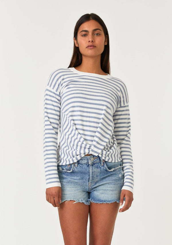 [Color: Ivory/Dusty Blue] A front facing image of a brunette model wearing a classic ivory and light blue striped knit pullover sweater. With long sleeves, a drop shoulder, a crew neckline, and a twist front detail at the waist. 