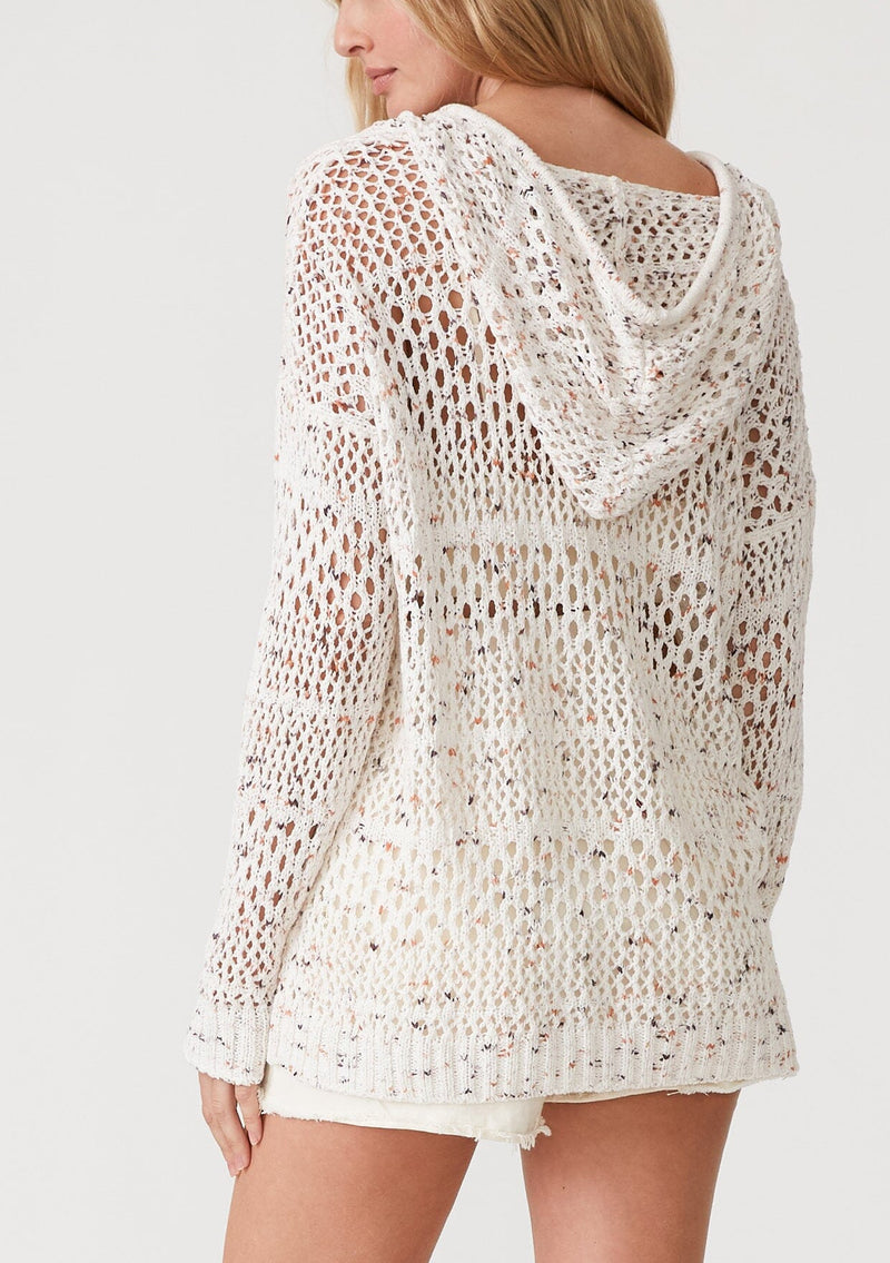 [Color: Ivory/Coral] A back facing image of a blonde model wearing a lightweight crochet hoodie in an ivory speckled knit. With long sleeves, a v neckline, a drawstring hoodie, and a dropped shoulder. 