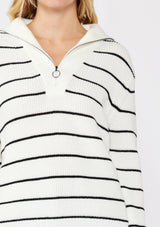 [Color: White/Black] A detail image of a blonde model wearing a white and black striped knit pullover sweater with a half zip front. 