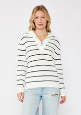 [Color: White/Black] A front facing image of a blonde model wearing a white and black striped knit pullover sweater with a half zip front. 