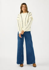 [Color: Cream/Black] A front facing image of a brunette model wearing a cozy striped knit sweater with a cable knit detailing. Featuring a crew neckline and  long sleeves with a dropped shoulder. A cold weather staple for the fall and winter season. 