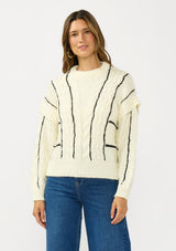 [Color: Cream/Black] A front facing image of a brunette model wearing a cozy striped knit sweater with a cable knit detailing. Featuring a crew neckline and  long sleeves with a dropped shoulder. A cold weather staple for the fall and winter season. 