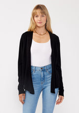 [Color: Black] A front facing image of a blonde model wearing a black solid knit sweater with a wrap front and side button closures. A soft versatile sweater, perfect for spring styling. 
