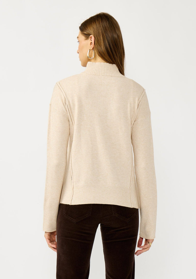 [Color: Dusty Blush] A back facing image of a blonde model wearing a cozy beige turtle neck sweater with a half zip front, long sleeves, and ribbed trims. A basic pullover sweater for the fall season. 