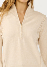 [Color: Dusty Blush] A detail image of a blonde model wearing a cozy beige turtle neck sweater with a half zip front, long sleeves, and ribbed trims. A basic pullover sweater for the fall season. 