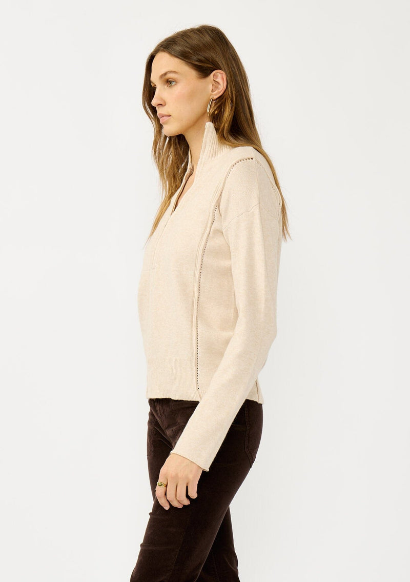 [Color: Dusty Blush] A side facing image of a blonde model wearing a cozy beige turtle neck sweater with a half zip front, long sleeves, and ribbed trims. A basic pullover sweater for the fall season. 