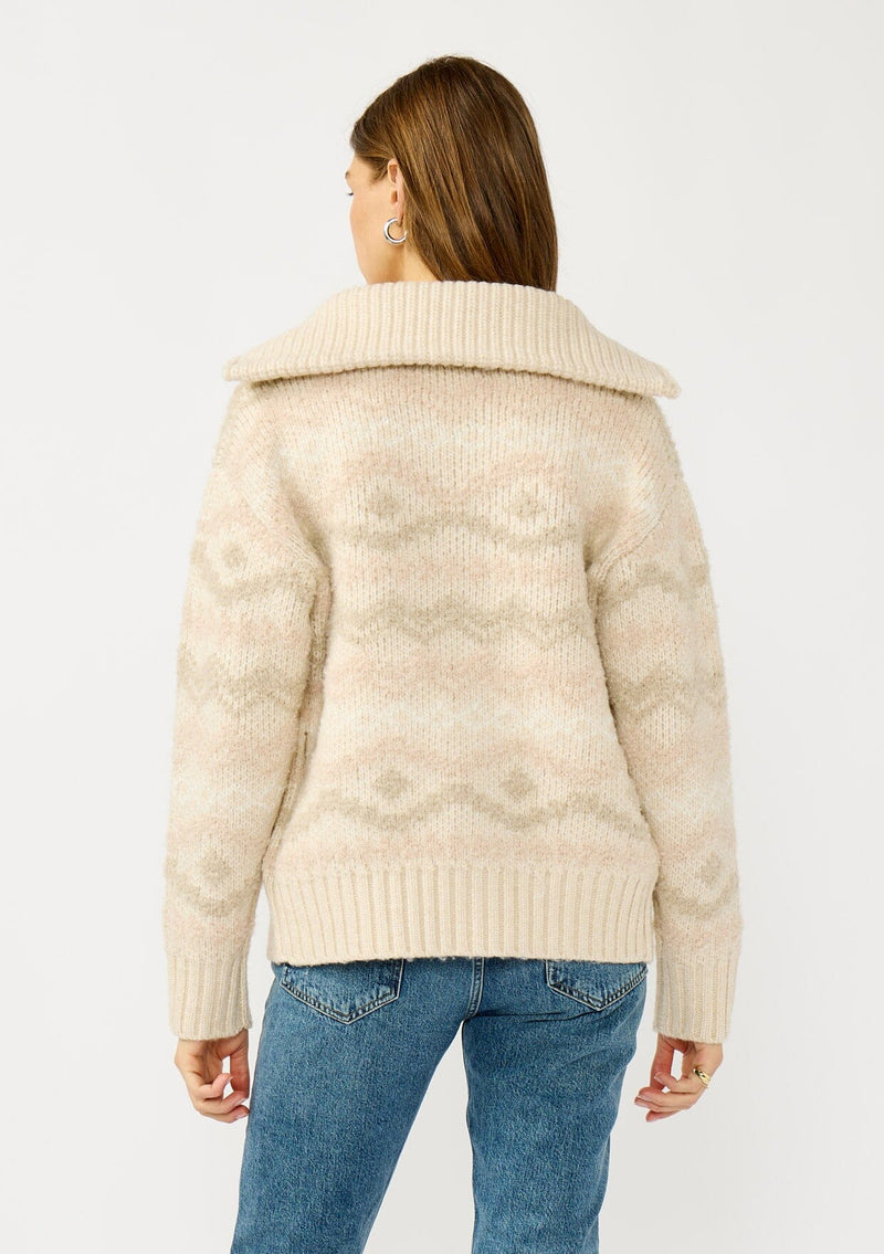 [Color: Natural/Dusty Pink] A back facing image of a blonde model wearing a beige southwestern boho sweater jacket with a zipper front and ribbed trims. A fall cozy sweater. 