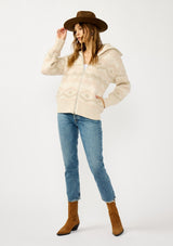 [Color: Natural/Dusty Pink] A front facing image of a blonde model wearing a beige southwestern boho sweater jacket with a zipper front and ribbed trims. A fall cozy sweater. 