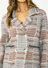 [Color: Charcoal] A detail image of a brunette model wearing a southwestern fuzzy jacket with a notched collar, button front, and patch pockets. 