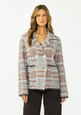 [Color: Charcoal] A front facing image of a brunette model wearing a southwestern fuzzy jacket with a notched collar, button front, and patch pockets. 